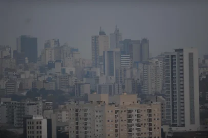 CAXIAS DO SUL, RS, BRASIL, 09/09/2024. Fumaça das queimadas encobre o céu em parte do Brasil e deixa o Sol avermelhado, inclusive no RS. Apesar de não haver nuvens, vestígios dos incêndios impedem a passagem total dos raios solares. Mesmo com tempo ensolarado em alguns regiões, dias estão cinzentos e com aspecto de nublado. Na foto, vistas gerais de Caxias. Pôr do sol, céu cinzento. (Porthus Junior/Agência RBS)Indexador: BTK                             <!-- NICAID(15861882) -->