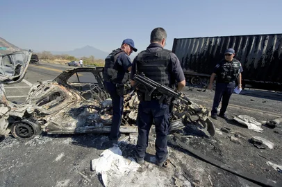 ALFREDO ESTRELLA / AFP Mexican Federal Police officers inspect the charred wreckage of a car used to make a barricade blocking the Apatzingan-Uruapan road, Michoacan State, Mexico, on December 11, 2010. Gunmen from La Familia cartel drug blocked several roads in Michoacan State during a confrontation between drug cartels and Federal Police, said the state government of Morelia. AFP PHOTO/Alfredo EstrellaEditoria: CLJLocal: URUAPANIndexador: ALFREDO ESTRELLASecao: CrimeFonte: AFPFotógrafo: STF<!-- NICAID(6385633) -->