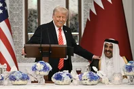 US President Donald Trump (L) speaks with Qatar's Emir Sheikh Tamim bin Hamad al-Thani at the start of a state dinner at the Lusail Palace in Doha on May 14, 2025. (Photo by Brendan SMIALOWSKI / AFP)<!-- NICAID(16038171) -->