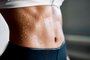 Close up of fit woman torso with sweat on skin after workout. Female with perfect abdomen musclesIndexador: Viktor GladkovFonte: 325707204<!-- NICAID(14646773) -->