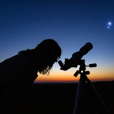 Woman looking at night sky with amateur astronomical telescope.Fonte: 398404157<!-- NICAID(15162468) -->