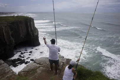 TORRES, RS, BRASIL, 22-01-2026: O pescador Osvaldino Teixeira, conhecido como "Vardo", pesca com a esposa, Fátima Teixeira, no costão no Morro das Furnas, em Torres. Foto: Mateus Bruxel/Agência RBSIndexador: MATEUS BRUXEL<!-- NICAID(16209504) -->