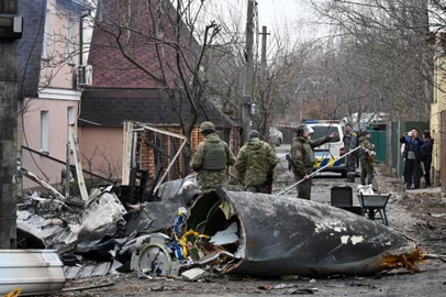 Ukrainian servicemen work by the wreckage of an unidentified aircraft which crashed into a  private house in a residential area in Kyiv on February 25, 2022. - Russian forces reached the outskirts of Kyiv on Friday as Ukrainian President Volodymyr Zelensky said the invading troops were targeting civilians and explosions could be heard in the besieged capital. Pre-dawn blasts in Kyiv set off a second day of violence after Russian President Vladimir Putin defied Western warnings to unleash a full-scale ground invasion and air assault on Thursday that quickly claimed dozens of lives and displaced at least 100,000 people. (Photo by GENYA SAVILOV / AFP)<!-- NICAID(15026564) -->
