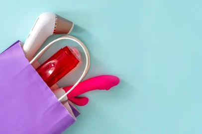 less Clitoral Stimulator layout, Vibrator and lubricant gel in a purple bag on a blue background. The concept of online sex shops and delivery of sex toys for adults. shopping online.Fonte: 521028167<!-- NICAID(15427073) -->