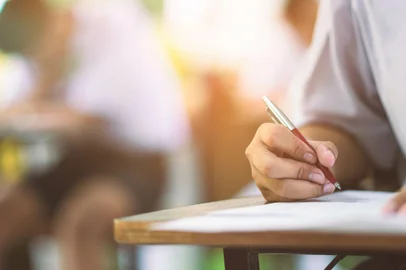 Closeup to hand of student  holding pen and taking exam in classroom with stress for education test . arrowsmith2 / stock.adobe.com<!-- NICAID(15749505) -->