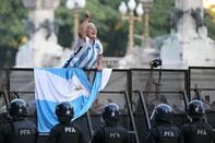 A woman wearing the Argentine national football team jersey shouts in front of the Argentine Federal Police (PFA) during a protest of pensioners against the government of Argentina's President Javier Milei outside the National Congress in Buenos Aires on March 19, 2025. Argentina's Congress on Wednesday gave President Javier Milei's government the green light to reach a new loan agreement with the International Monetary Fund. Milei asked lawmakers to approve a new 10-year loan, on top of the $44 billion Argentina already borrowed in 2018, to boost the central bank's foreign currency reserves and cover looming debt payments. (Photo by Juan Mabromata / AFP)<!-- NICAID(15999165) -->