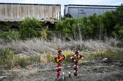 Cruz e velas são mantidas no local onde um trailer foi descoberto com imigrantes dentro, nos arredores de San Antonio, Texas, em 28 de junho de 2022. - As autoridades dos EUA abriram uma investigação criminal na terça-feira depois que 50 imigrantes lotados em um trailer sufocante morreram no Texas, com o presidente Joe Biden culpando os contrabandistas profissionais pela tragédia. (Foto por CHANDAN KHANNA / AFP)<!-- NICAID(15135009) -->