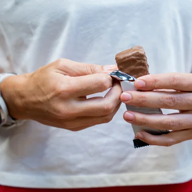 A fit woman in a gym holds a protein bar enjoying a healthy and nutritious snack to boost energy and support muscle recovery<!-- NICAID(16138871) -->