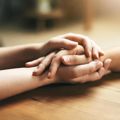 Holding hands, comfort and support of friends, care and empathy together on table in home mockup. Kindness, love and women hold hand for hope, trust or prayer, solidarity or compassion, help or unityMãos. Foto: Diane Munro/peopleimages.com/stock.adobe.comIndexador: Yuri Arcurs peopleimages.comFonte: 603294656<!-- NICAID(15786324) -->