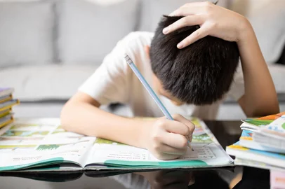 Asian kid boy holding head in hand,schoolboy study hard,tired from studying,Stressed male student while doing homework,child experienced difficulties in learning,health care and education conceptFonte: 802667138<!-- NICAID(15911965) -->
