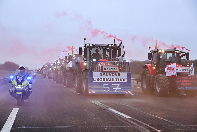 Farmers riding their tractor displaying a banner which reads as "Let's save agriculture" and roadsigns turned upside down, coming from Meuse and Moselle and escorted by a motocycle Police officers, arrive to block the A4 highway near Jossigny, east of Paris on January 30, 2024, amid nationwide protests called by several farmers unions on pay, tax and regulations. Farmers protests across Europe are growing as they demand better conditions to grow produce and maintain a proper income. (Photo by Bertrand GUAY / AFP)<!-- NICAID(15664060) -->
