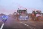 Farmers riding their tractor displaying a banner which reads as "Let's save agriculture" and roadsigns turned upside down, coming from Meuse and Moselle and escorted by a motocycle Police officers, arrive to block the A4 highway near Jossigny, east of Paris on January 30, 2024, amid nationwide protests called by several farmers unions on pay, tax and regulations. Farmers protests across Europe are growing as they demand better conditions to grow produce and maintain a proper income. (Photo by Bertrand GUAY / AFP)<!-- NICAID(15664060) -->