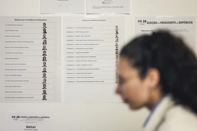 PATRICIA DE MELO MOREIRA / AFP A woman passes by a billboard with the list of candidates for Portugals Presidential elections at a polling station in Caldas da Rainha, north of Lisbon on January 18, 2026. Portugal started voting in the first round of a presidential election in which a far-right candidate could for the first time make it to a run-off, but with the final result hard to call. (Photo by PATRICIA DE MELO MOREIRA / AFP)<!-- NICAID(16206179) -->