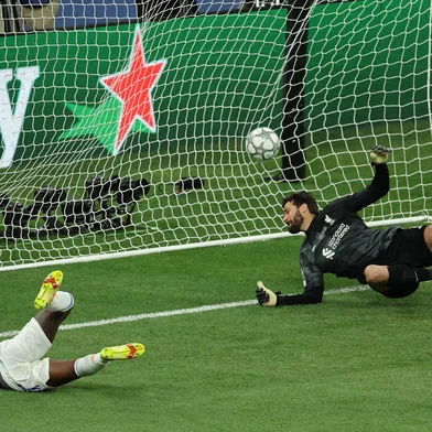 Real Madrid's Brazilian forward Vinicius Junior (L) scores the opening goal past Liverpool's Brazilian goalkeeper Alisson Becker during the UEFA Champions League final football match between Liverpool and Real Madrid at the Stade de France in Saint-Denis, north of Paris, on May 28, 2022. (Photo by Thomas COEX / AFP)<!-- NICAID(15109744) -->
