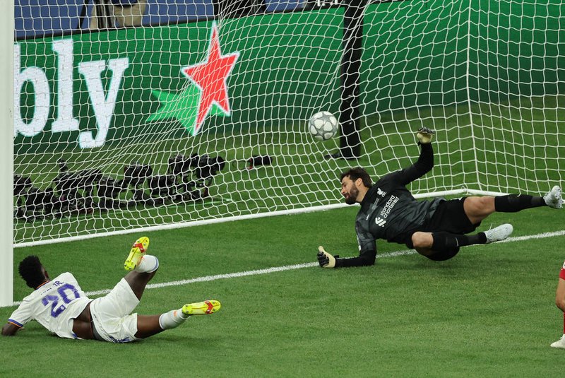 Real Madrid's Brazilian forward Vinicius Junior (L) scores the opening goal past Liverpool's Brazilian goalkeeper Alisson Becker during the UEFA Champions League final football match between Liverpool and Real Madrid at the Stade de France in Saint-Denis, north of Paris, on May 28, 2022. (Photo by Thomas COEX / AFP)<!-- NICAID(15109744) -->