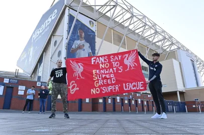 Leeds United fans hold a banner against plans for a European Super League and the involvement of Liverpool football club outside Elland Road ahead of the English Premier League football match between Leeds United and Liverpool in Leeds, northern England, on April 19, 2021. - Twelve of Europe's biggest clubs on Monday said they planned to launch a breakaway Super League, despite the threat of an international ban for them and their players. "AC Milan, Arsenal, Atletico Madrid, Chelsea, Barcelona, Inter Milan, Juventus, Liverpool, Manchester City, Manchester United, Real Madrid and Tottenham Hotspur have all joined as founding clubs," said a statement by the group. (Photo by Paul ELLIS / AFP)Editoria: SPOLocal: LeedsIndexador: PAUL ELLISSecao: soccerFonte: AFPFotógrafo: STF<!-- NICAID(14761287) -->