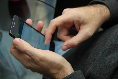 Homem utilizando seu smartphone para enviar mensagens a um contato.<!-- NICAID(15279520) -->