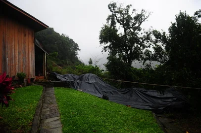 CAXIAS DO SUL, RS, BRASIL, 13/05/2024. Os geólogos da Secretaria do Meio Ambiente, com o apoio da Secretaria da Habitação e da Guarda Municipal, identificaram novas fissuras na encosta de Galópolis devido ao excesso de chuvas das últimas horas. Desta vez, a movimentação ocorreu atrás do Sindicato Têxtil, à direita da BR-116, onde já ocorreu deslizamento de terra atingindo o cartório e o CRVA do bairro. Foram colocadas lonas para proteger a área da água. (Porthus Junior/Agência RBS)<!-- NICAID(15762770) -->