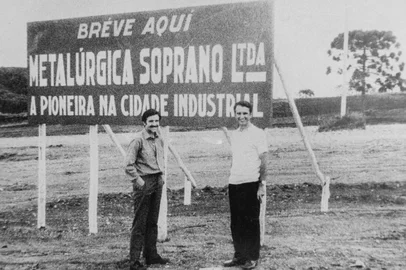 Adelino Miotti (E) e ...  posam junto à placa que anunciava a chegada da Metalúrgica Soprano ao Distrito Industrial, em Farroupilha, nos anos 1970. Empresa começou como uma fábrica de gaitas e acordeons em 1954, em Caxias do Sul.<!-- NICAID(16122010) -->