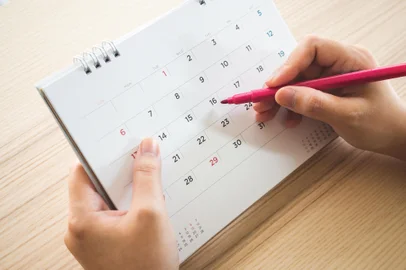Hand with pen writing on calendar page closeup<!-- NICAID(15679454) -->