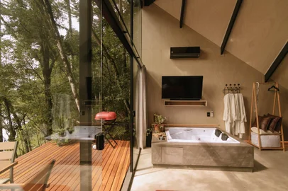 Área íntima: aberturas convidam à contemplação da paisagem. A tevê, com 'soundbar', está posicionada para ser usufruída da cama ou da banheira. A iluminação foi projetada para mais aconchego.<!-- NICAID(15647349) -->