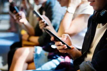 Group of young adult friends using smartphones in the subway. Adolescentes usando celular, Adolecentes bullying digital, redes sociais, telas<!-- NICAID(16255656) -->