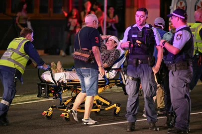 Health workers move a woman on a stretcher to an ambulance after a shooting incident at Bondi Beach in Sydney on December 14, 2025. Australian police said two people were in custody following reports of multiple gunshots on December 14 at Sydney's famed Bondi Beach, urging the public to take shelter. (Photo by Saeed KHAN / AFP)<!-- NICAID(16186382) -->