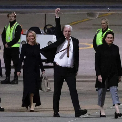 WikiLeaks founder Julian Assange (C) raises his fist after arriving at Canberra Airport in Canberra on June 26, 2024, after he pleaded guilty at a US court in Saipan to a single count of conspiracy to obtain and disseminate US national defence information. WikiLeaks founder Julian Assange returned home to Australia to start life as a free man June 26 after admitting he revealed US defence secrets in a deal that unlocked the door to his London prison cell. (Photo by David GRAY / AFP)<!-- NICAID(15800486) -->