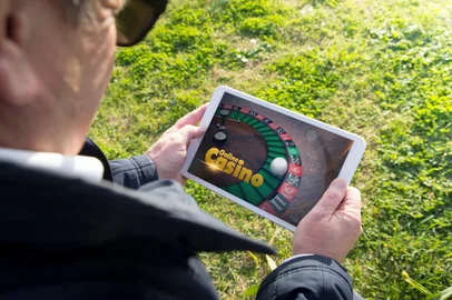 Old man holding digital tablet pc with casino app. All screen graphics are made up.<!-- NICAID(16201048) -->