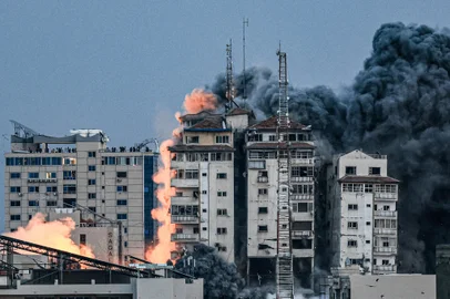 EDITORS NOTE: Graphic content / (FILES) People standing on a rooftop watch as a ball of fire and smoke rises above a building in Gaza City on October 7, 2023 during an Israeli air strike that hit the Palestine Tower building. Hamas's multipronged attack on southern Israel on October 7 was unprecedented in scale. The panic and confusion it caused made many details of what was happening difficult to establish immediately. (Photo by MAHMUD HAMS / AFP)Editoria: WARLocal: Gaza CityIndexador: MAHMUD HAMSSecao: armed conflictFonte: AFPFotógrafo: STF<!-- NICAID(15873399) -->