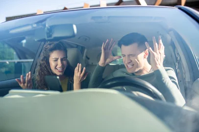 Man and woman swearing in a car*A PEDIDO DE NIKOLAS MONDADORI* Conflict. Young adult man and woman with closed eyes open mouth arms raised sitting in car - Foto: zinkevych/stock.adobe.comFonte: 356865719<!-- NICAID(15116822) -->