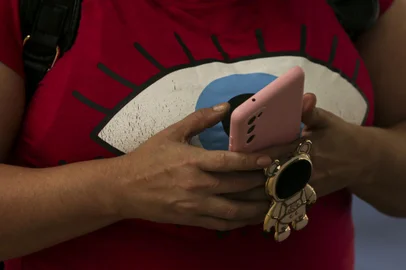 Porto Alegre, RS, Brasil, 28-12-2023: Mulher com celular no Terminal Parobé. Polícia militar dá dicas de segurança para quem circula a pé ou utiliza transporte coletivo na região central no período em que a cidade costuma estar mais vazia. Entre condutas de risco, que devem ser evitadas: uso do celular, fones de ouvido, mochilas nas costas. Foto: Mateus Bruxel / Agência RBSIndexador: Mateus Bruxel<!-- NICAID(15636320) -->