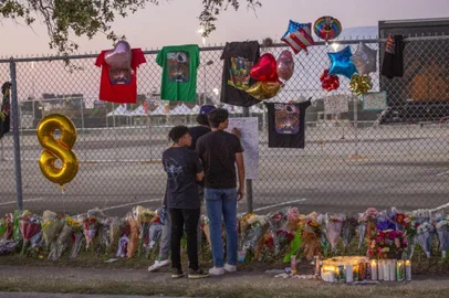 (FILES) In this file photo taken on November 07, 2021 seventeen years old local high School friends who attended the Travis Scott concert, Isaac Hernandez and Matthias Coronel watch Jesus Martinez sign a remembrance board at a makeshift memorial at the NRG Park grounds where eight people died in a crowd surge at the Astroworld Festival in Houston, Texas. - A 22-year-old university student caught up in the crowd that rushed the stage at a rap concert in Texas last week has died of her injuries, her family said November 11, 2021, raising the death toll from the incident to nine. (Photo by Thomas Shea / AFP)<!-- NICAID(14939207) -->