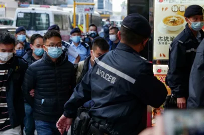 Stand News chief editor Patrick Lam (2nd L, foreground) is brought to the news outlet's office building in handcuffs after police were deployed to search the premises in Hong Kong's Kwun Tong district on December 29, 2021. (Photo by Daniel SUEN / AFP)<!-- NICAID(14978626) -->