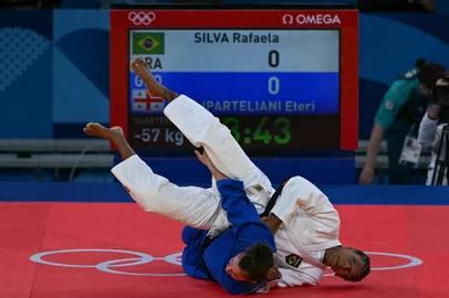 Brazil's Rafaela Silva and Georgia's Eteri Liparteliani (Blue) compete in the judo women's -57kg quarter-final bout of the Paris 2024 Olympic Games at the Champ-de-Mars Arena, in Paris on July 29, 2024. (Photo by Luis ROBAYO / AFP)<!-- NICAID(15825421) -->