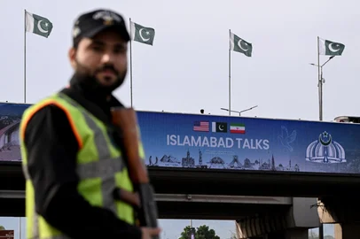 A policeman stands guard in front of a digital screen displaying news of USIran peace talks along a road in Islamabad on April 10, 2026. A cloud of uncertainty hung April 10 over the scheduled start of talks in Pakistan between the United States and Iran, with no announcement yet on the arrival of negotiators and both sides accusing the other of failing to properly implement a fragile ceasefire. (Photo by Farooq NAEEM / AFP)<!-- NICAID(16263809) -->