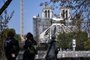 As pessoas olham para a Catedral de Notre-Dame de Paris, em 14 de abril de 2021, durante as obras de reconstrução, enquanto 15 de abril de 2021 marcará o aniversário de dois anos do incêndio que devastou a Catedral, no centro da capital francesa, Paris. (Foto de Anne-Christine POUJOULAT / AFP)<!-- NICAID(14761035) -->