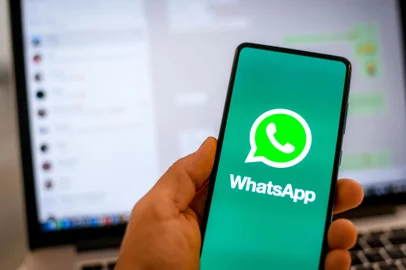 Close up view of hand with smartphone and Whatsapp âlogo on display. Laptop on background. New technology, social media,  network, communication,  concept. Milan, Italy - October 2021<!-- NICAID(15892546) -->