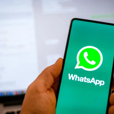 Close up view of hand with smartphone and Whatsapp âlogo on display. Laptop on background. New technology, social media,  network, communication,  concept. Milan, Italy - October 2021<!-- NICAID(15892546) -->