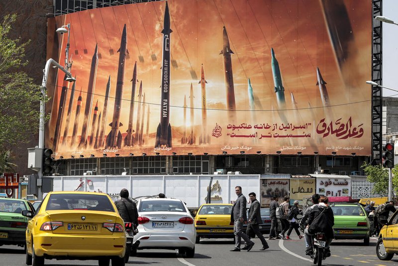 A man walks across a pedestrian crossing near a billboard depicting named Iranian ballistic missiles in service, with text in Arabic reading "the honest [person's] promise" and in Persian "Israel is weaker than a spider's web", in Valiasr Square in central Tehran on April 15, 2024. Iran on April 14 urged Israel not to retaliate militarily to an unprecedented attack overnight, which Tehran presented as a justified response to a deadly strike on its consulate building in Damascus. (Photo by ATTA KENARE / AFP)Editoria: WARLocal: TehranIndexador: ATTA KENARESecao: conflict (general)Fonte: AFPFotógrafo: STF<!-- NICAID(15735128) -->