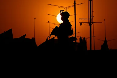 An Iraqi soldier stands guard as people march during celebrations to mark the ceasefire between Israel and Iran in the southern city of Basra on June 24, 2025. Iranian President Masoud Pezeshkian announced the "end of the 12-day war" imposed by Israel, in a message to the nation carried by the official IRNA news agency on June 24. (Photo by Hussein FALEH / AFP)Editoria: WARLocal: BasraIndexador: HUSSEIN FALEHSecao: warFonte: AFPFotógrafo: STR<!-- NICAID(16066394) -->