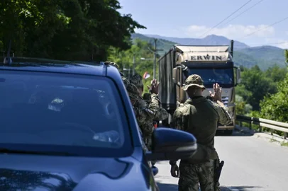 NATO soldiers greet a truck driver near the town of Zubin Potok on August 1, 2022. - Serbs in North Kosovo removed barricades on August 1 that closed two crossings along the border with Serbia after authorities in Pristina postponed the implementation of new travel measures that sparked tensions. Trucks and barriers were being cleared from the roads, according to an AFP reporter, hours after a string of shootings and air raid sirens in northern Kosovo sent tensions soaring in the disputed territory home to both Serbs and ethnic Albanians. (Photo by Armend NIMANI / AFP)<!-- NICAID(15164668) -->