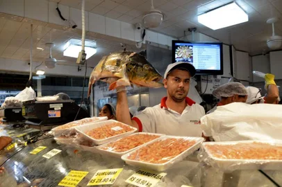 **FOTO INDEXADA A PEDIDO DE CÁSSIA OLIVEIRA**Homem segura peixe em feira de pescados.<!-- NICAID(15442352) -->