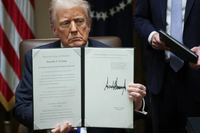 WASHINGTON, DC - MARCH 25: U.S. President Donald Trump holds an executive order he signed during an Ambassador Meeting in the Cabinet Room of the White House on March 25, 2025 in Washington, DC. During the meeting, Trump answered questions from reporters on the news that Jeffrey Goldberg, the editor-in-chief of The Atlantic magazine, was accidentally added to a Signal group chat of top administration officials, where highly sensitive national security information was discussed.   Win McNamee/Getty Images/AFP (Photo by WIN MCNAMEE / GETTY IMAGES NORTH AMERICA / Getty Images via AFP)<!-- NICAID(16003483) -->