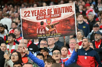 A hopeful Arsenal fan holds up a banner reading 22 years of waiting ends this season, during the English Premier League football match between Arsenal and Burnley at the Emirates Stadium in London on May 18, 2026. (Photo by Glyn KIRK / AFP) / RESTRICTED TO EDITORIAL USE. No use with unauthorized audio, video, data, fixture lists, club/league logos or 'live' services. Online in-match use limited to 120 images. An additional 40 images may be used in extra time. No video emulation. Social media in-match use limited to 120 images. An additional 40 images may be used in extra time. No use in betting publications, games or single club/league/player publications. / <!-- NICAID(16288619) -->