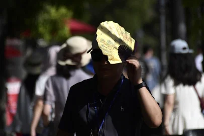 A tourist uses a fan to shield himself from the sun as he walks on a street in Seville on July 23, 2024, as temperatures rise across southern Europe during a heatwave. July 21, 2024 was the hottest day ever registered globally, according to preliminary data published on July 23, 2024 by the EU's climate monitor. The Copernicus Climate Change Service (C3S) said the global average surface air temperature on July 21 was 17.09 degrees Celsius, a fraction above the previous record set in 2023. (Photo by CRISTINA QUICLER / AFP)Editoria: HUMLocal: SevilleIndexador: CRISTINA QUICLERSecao: global changeFonte: AFPFotógrafo: STR<!-- NICAID(15828130) -->