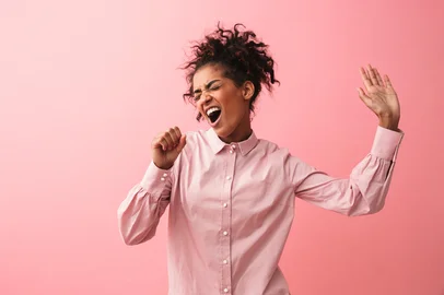 Beautiful young african woman posing isolated over pink wall background screaming singing.PORTO ALEGRE, RS, BRASIL, 18-09-2025: Mulher cantando e dançando. Foto: Drobot Dean/stock.adobe.comIndexador: Vadym DrobotFonte: 250437775<!-- NICAID(16127941) -->