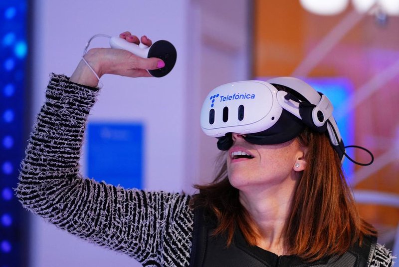 A woman experiences virtual reality glasses device at the Telefonica's stand during the Mobile World Congress (MWC), the telecom industry's biggest annual gathering, in Barcelona on February 26, 2024. The world's biggest mobile phone fair throws open its doors in Barcelona with the sector looking to artificial intelligence to try and reverse declining sales. (Photo by PAU BARRENA / AFP)Editoria: FINLocal: BarcelonaIndexador: PAU BARRENASecao: telecommunication equipmentFonte: AFPFotógrafo: STR<!-- NICAID(15689890) -->