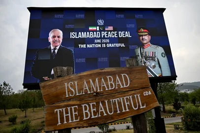 Commuters ride past an electronic board featuring Pakistan's Prime Minister Shehbaz Sharif (L) with Army Chief and Field Marshal Syed Asim Munir, displayed in front of the Serena Hotel in Islamabad on June 17, 2026, after the USIran peace deal announcement. Top officials from the United States and Iran will meet at a luxury mountainside resort in Switzerland on June 19, to sign a deal -- which Pakistan has helped mediate -- to bring the Middle East war to an end. (Photo by Aamir QURESHI / AFP)<!-- NICAID(16308714) -->