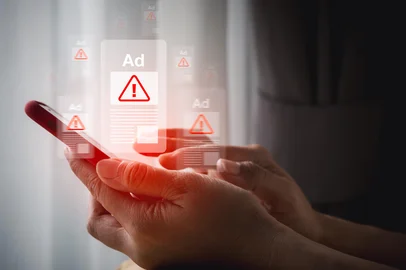 Hand holding smartphone with scam ad warning popups symbolizes online advertising fraud, scam detection, ad clickbait, cybersecurity risk, malicious content, and digital threat awareness.Fonte: 1800887826<!-- NICAID(16175560) -->